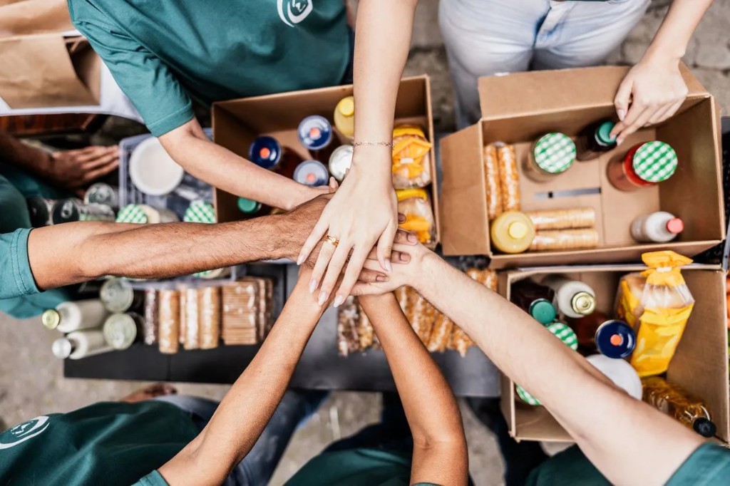 Volunteers with hands together over boxes of food donations
