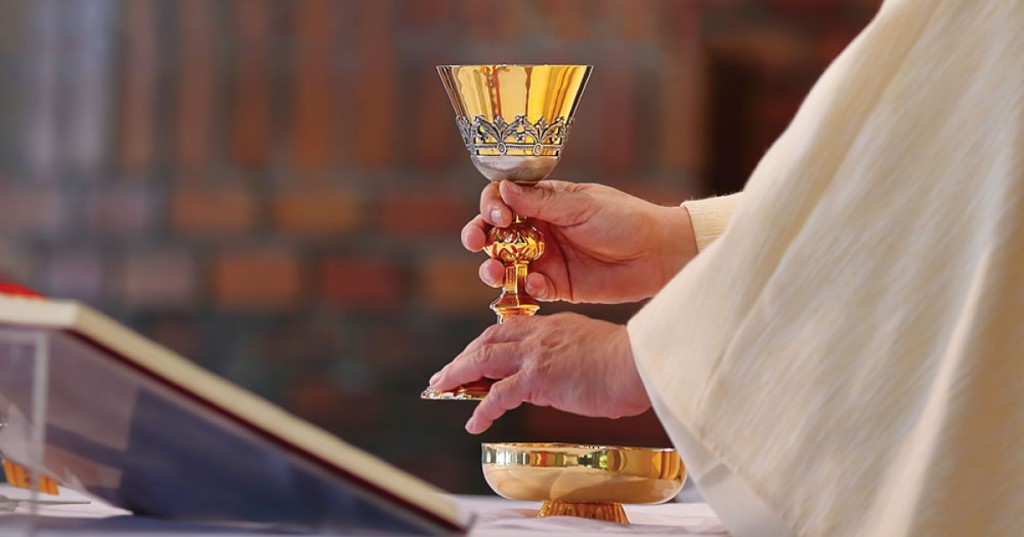 Priest with gold chalice and paten at the altar — Holy Mass